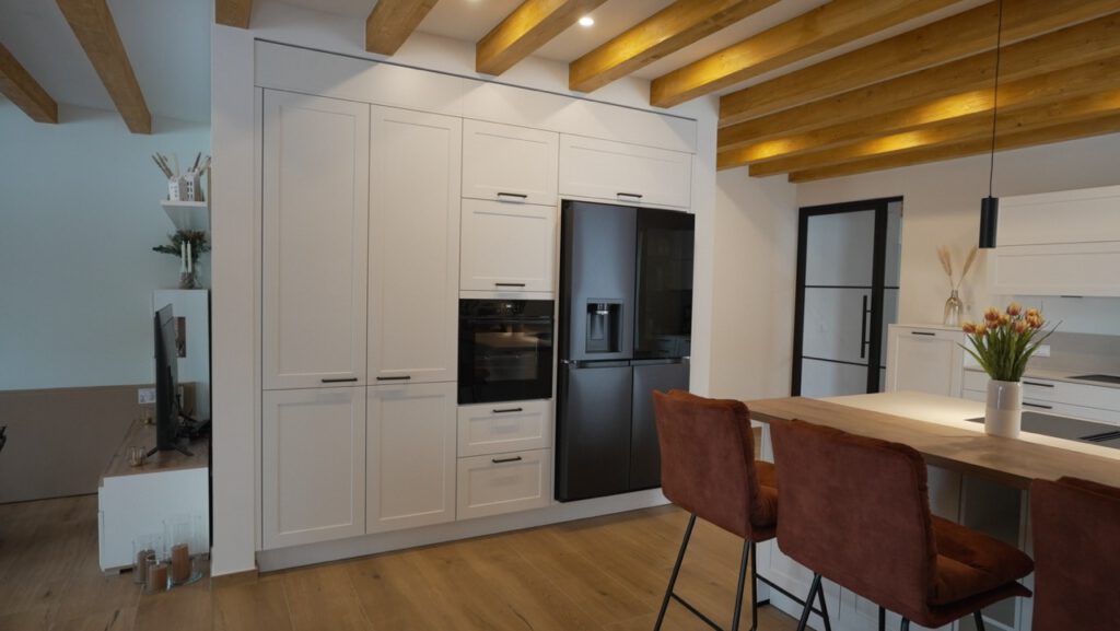 Moderne, aufgeräumte Küche mit weißen Schränken, Holzarbeitsplatte und Tulpen auf der Insel.