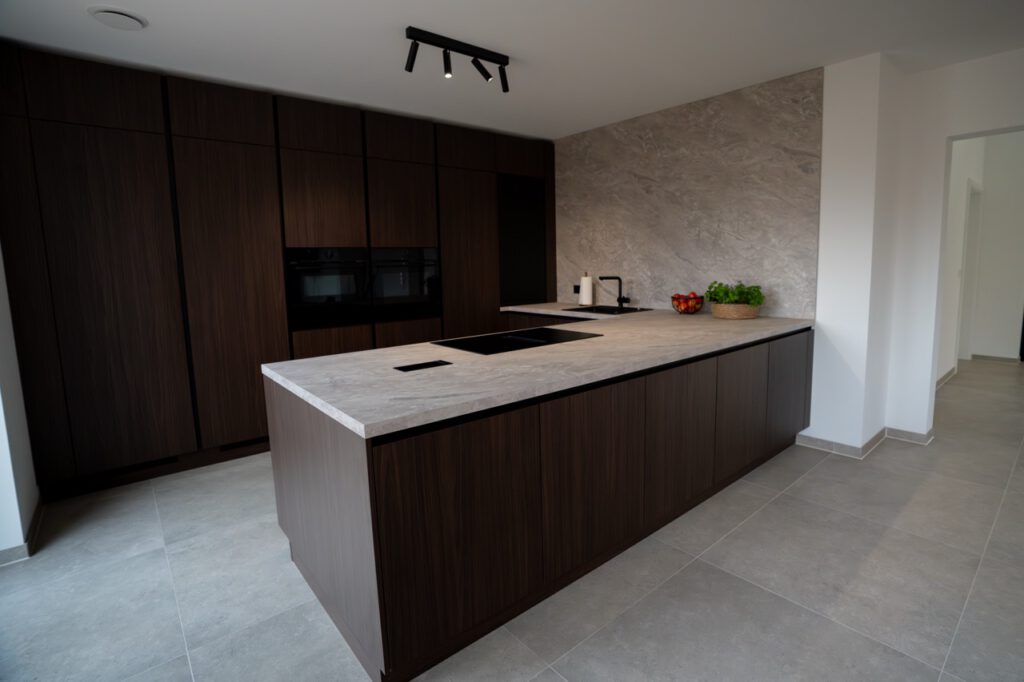 Moderne Küche mit grauer Steininsel, dunklen Holzschränken und minimalistischem Design.