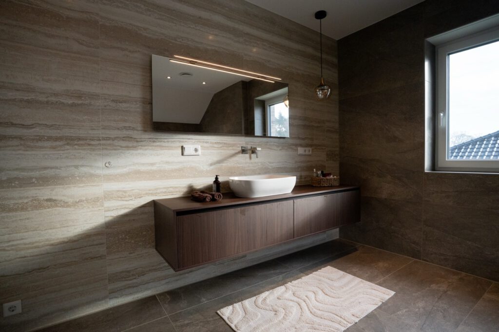 Modernes Badezimmer mit elegantem Design, warmen Erdtönen, hängendem Waschtisch und natürlichem Licht.