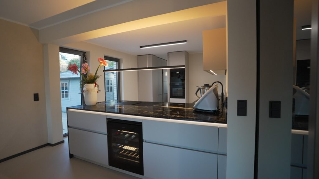 Moderne Küche mit dunkler Arbeitsplatte, rosa Blumen, Küchengerät und eingebautem Backofen.
