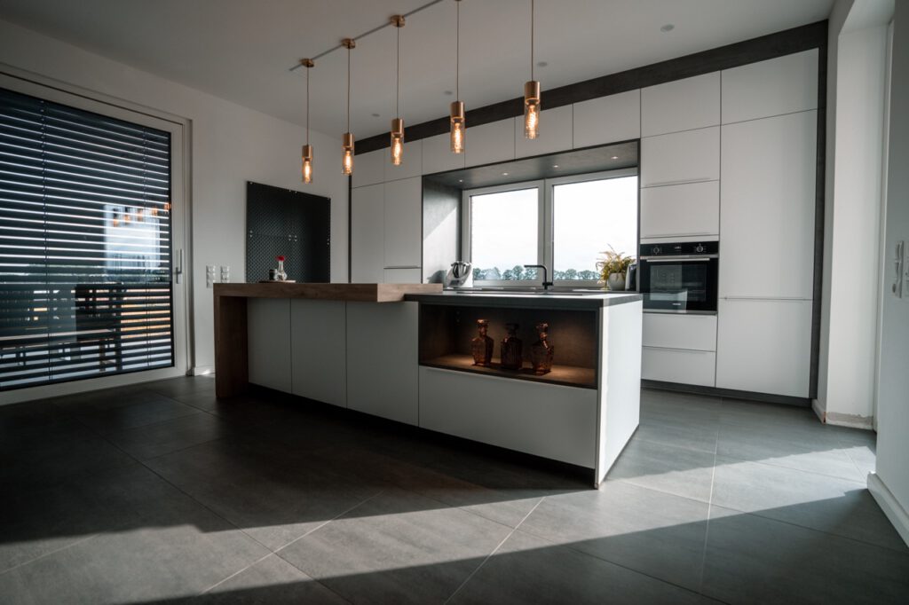Moderne, minimalistische Küche mit Holzarbeitsplatte, viel Licht und warmem, einladendem Ambiente.
