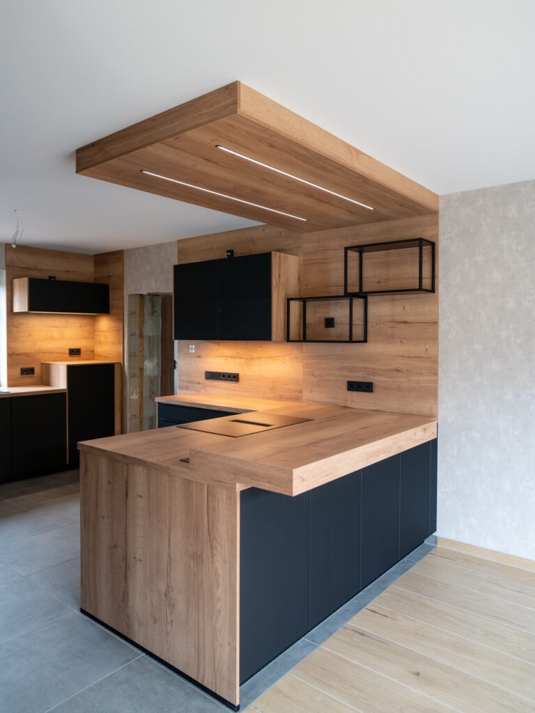 Moderne Küche mit Holzinsel, schwarzen Schränken und warmer Beleuchtung in elegantem Design.