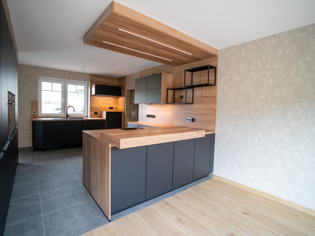 Moderne, minimalistische Küche mit Holzarbeitsplatte, schwarzen Schränken und Einbaugeräten.