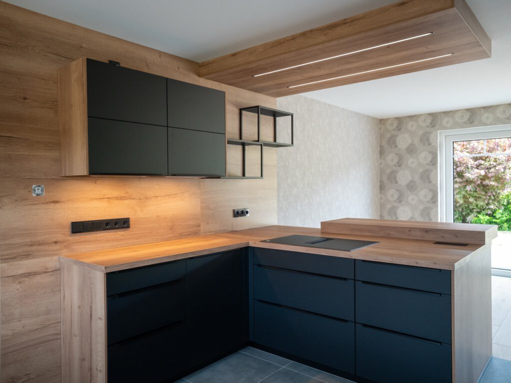 Moderne Küche mit mattschwarzen Schränken, Holzarbeitsflächen und gemütlicher Holzverkleidung.