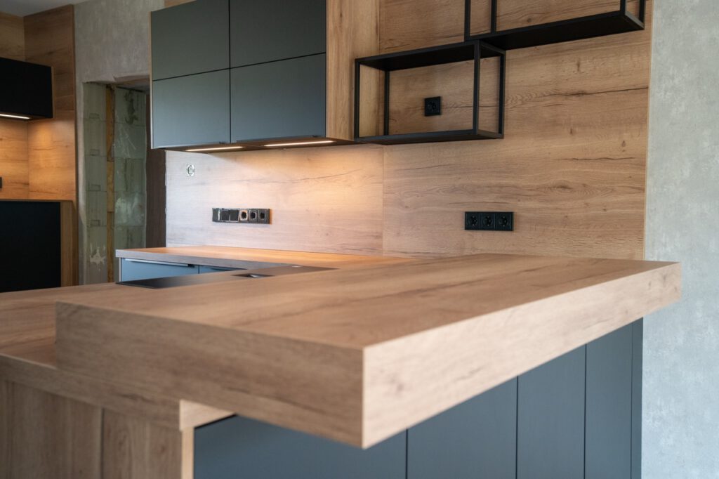 Moderne Küche mit Holzarbeitsplatte, dunklen Schränken und offenen Metallregalen, minimalistisch gestaltet.