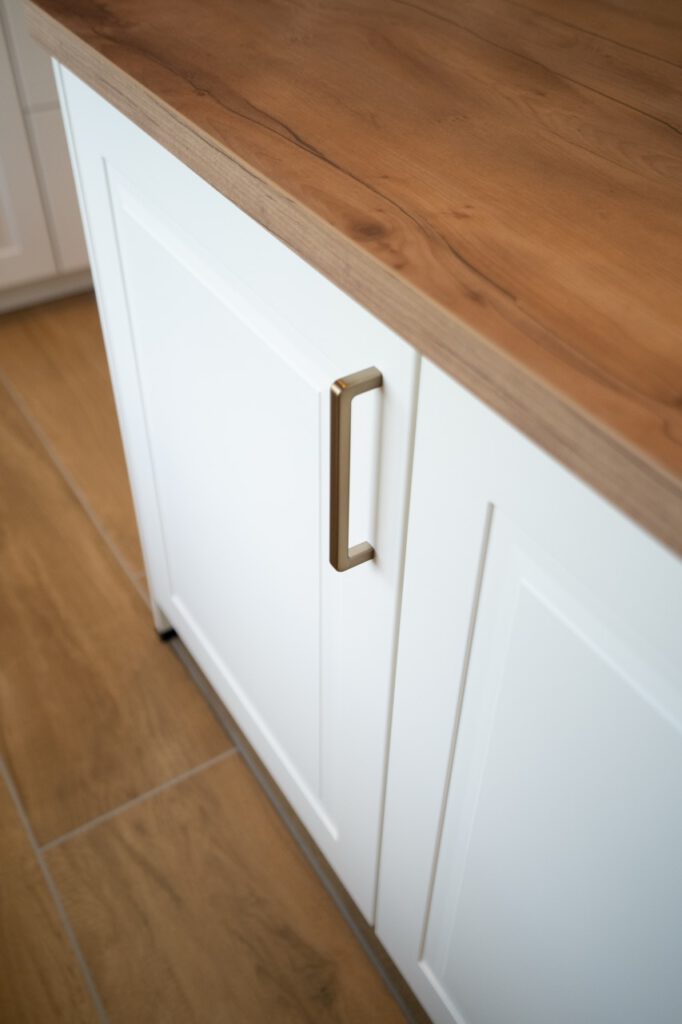 Moderne Küche mit weißem Schrank, Holzarbeitsplatte und hellem Holzboden; minimalistisch und einladend.