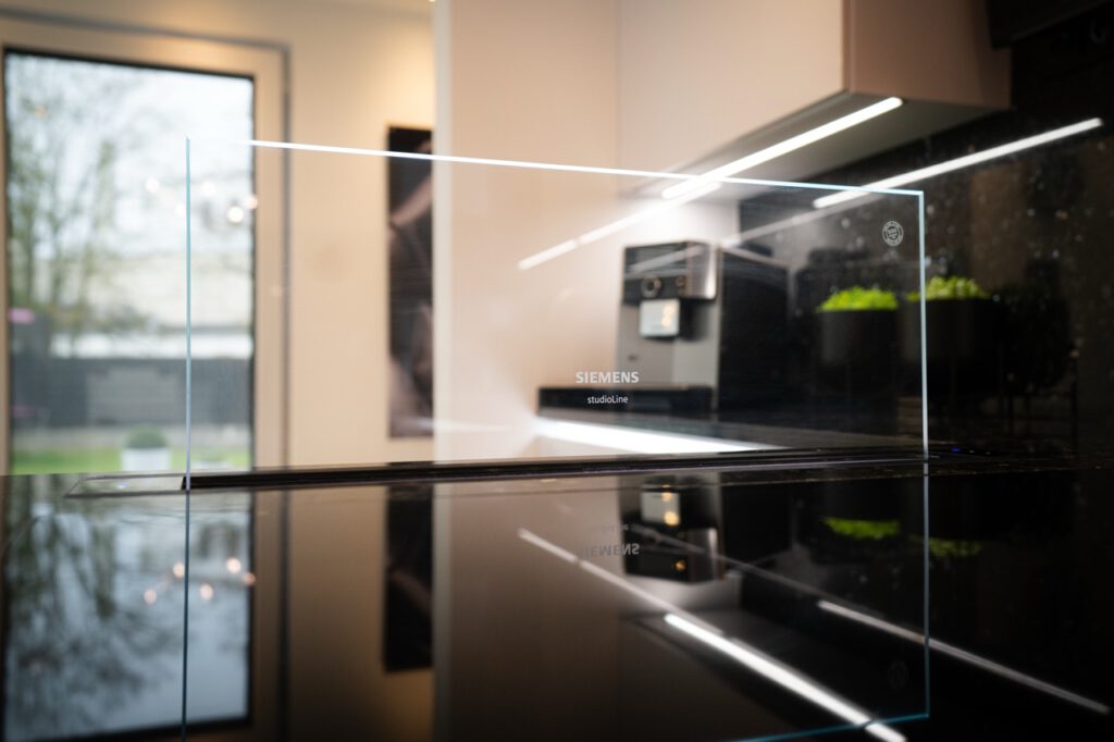 Moderne Küche mit Siemens-Gerät, glänzender Arbeitsplatte und grünen Pflanzen im Hintergrund.