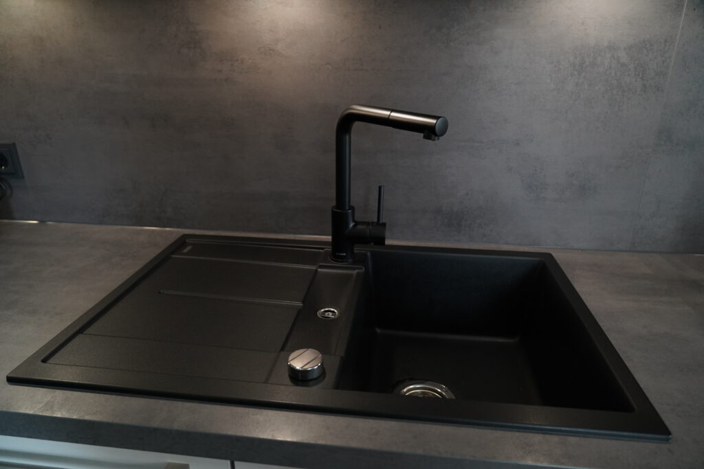 Moderne Küchenspüle mit schwarzem Wasserhahn, dunklen Tönen und minimalistischer Eleganz.