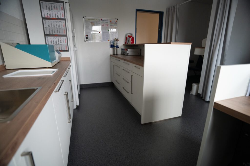 Ein klinischer Raum mit Laborgeräten, Arbeitsflächen, einem Whiteboard und einem Feuerlöscher.
