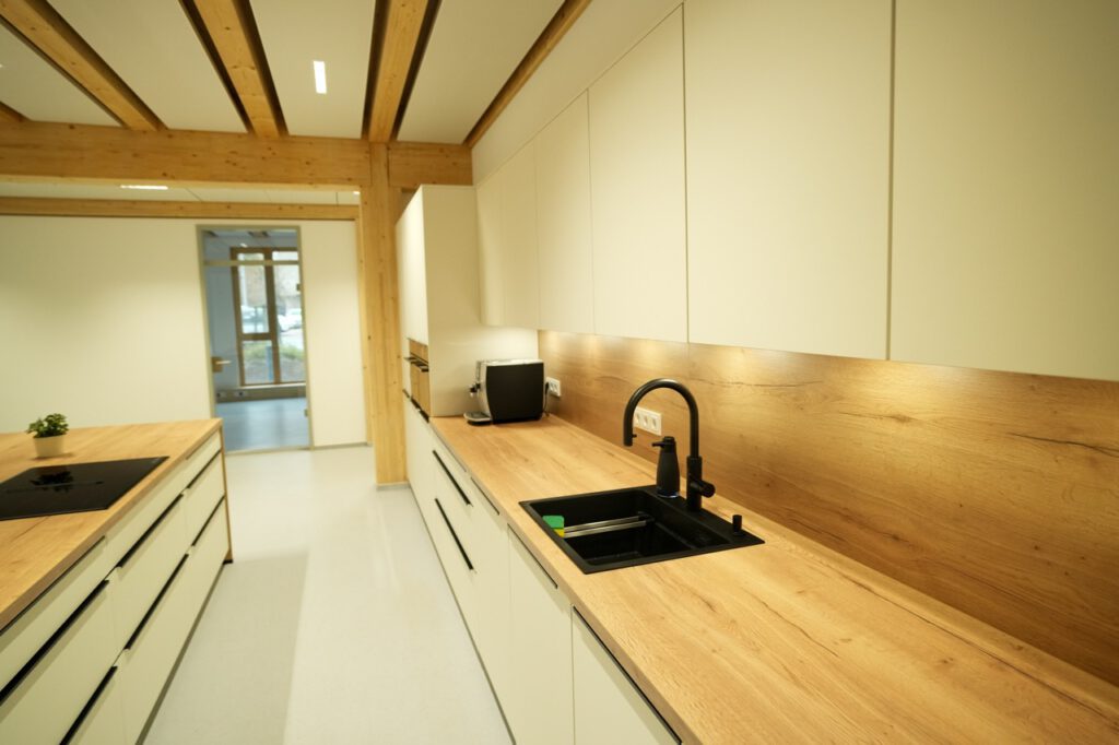 Moderne, minimalistische Küche mit heller Einrichtung, Holzarbeitsplatten und schwarzem Spülbecken.