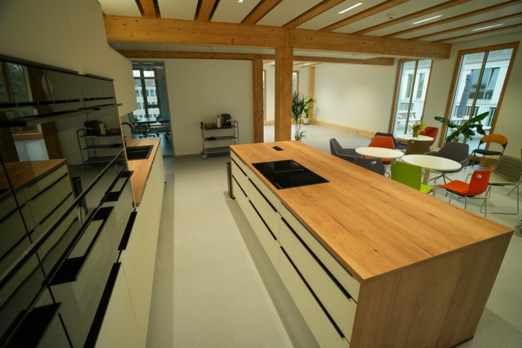 Moderner Küchen- und Essbereich mit Holzarbeitsplatte, bunten Stühlen und Pflanzen in einem Büro.