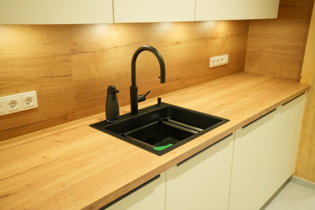 Moderne Küche mit Holzarbeitsplatte, schwarzem Waschbecken und warmem, einladendem Ambiente.