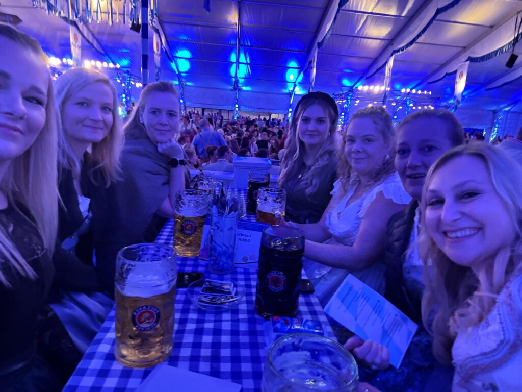 Menschen in Festzelt lächeln mit Bierkrügen, typisch bayerisches Fest, fröhliche Atmosphäre.
