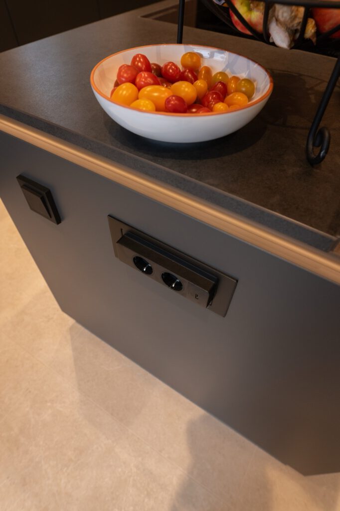 Eine moderne Küche mit einer Schale bunter Tomaten auf einer dunklen Arbeitsplatte.