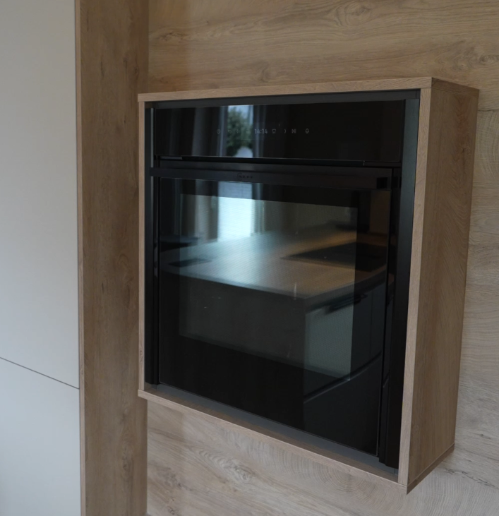Moderner schwarzer Einbaubackofen mit Glasfront in einer Küche mit hellen Holztönen.