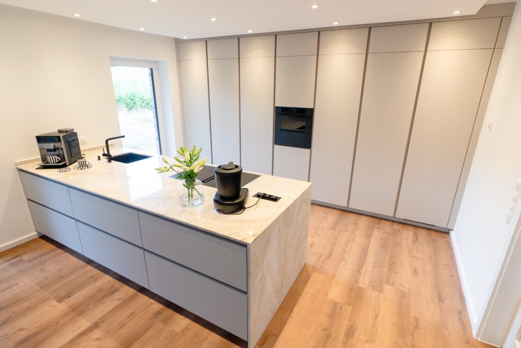 Moderne, minimalistische Küche mit heller Insel, integriertem Spülbecken und dekorativen weißen Lilien.