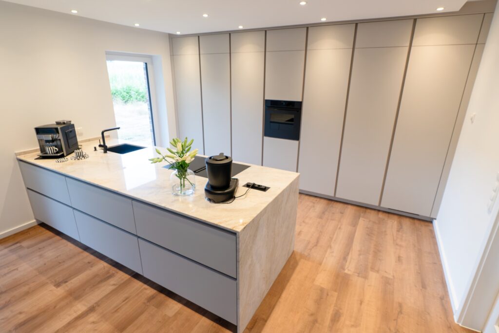 Moderne, minimalistische Küche mit heller Kücheninsel, weißen Lilien und neutraler Farbpalette.