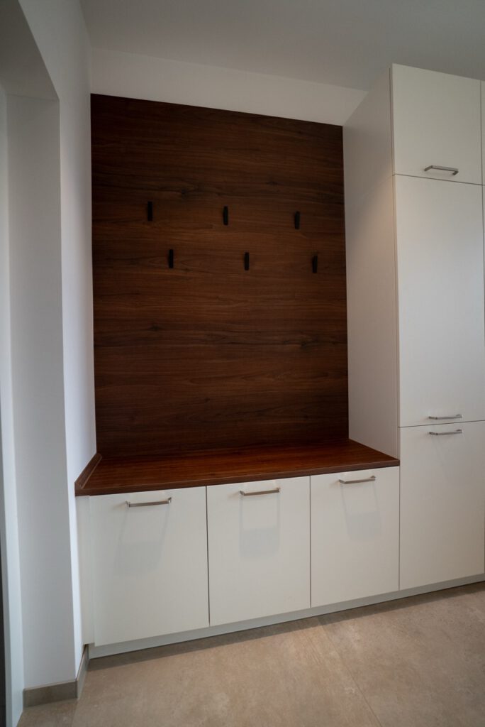 Moderner Raum mit weißen Schränken, Holzarbeitsplatte und schwarzen Haken an der Wand.