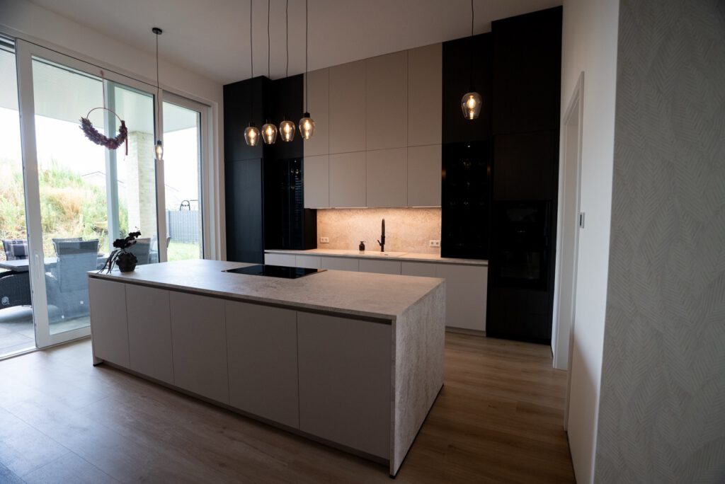 Moderne, minimalistische Küche mit heller Insel, schwarzen Schränken und warmem Holzfußboden.