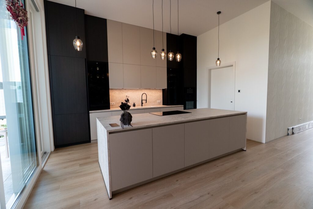 Moderne, minimalistische Küche mit heller Insel, dunklen Schränken und hängenden Lampen.