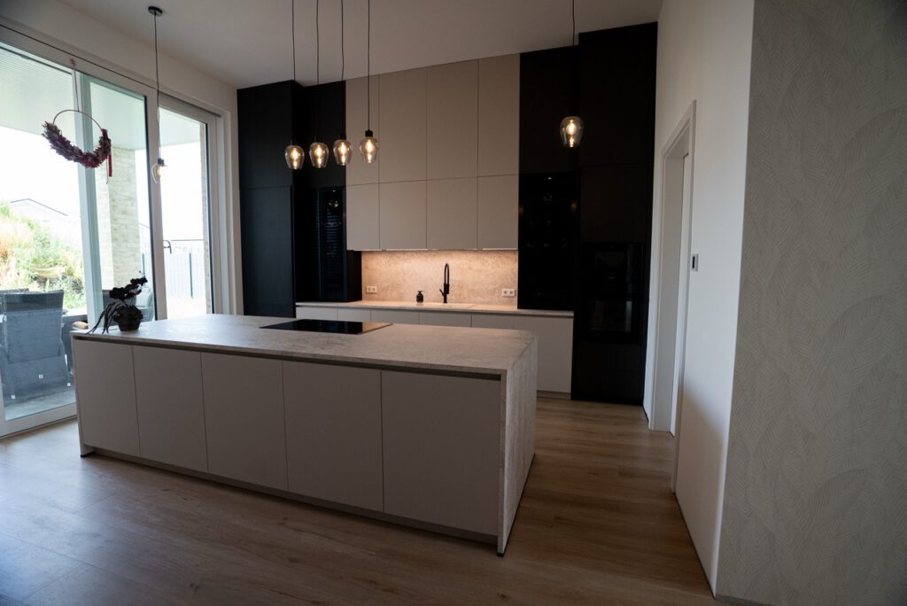Moderne, minimalistische Küche mit heller Insel, stilvollen Pendelleuchten und viel natürlichem Licht.