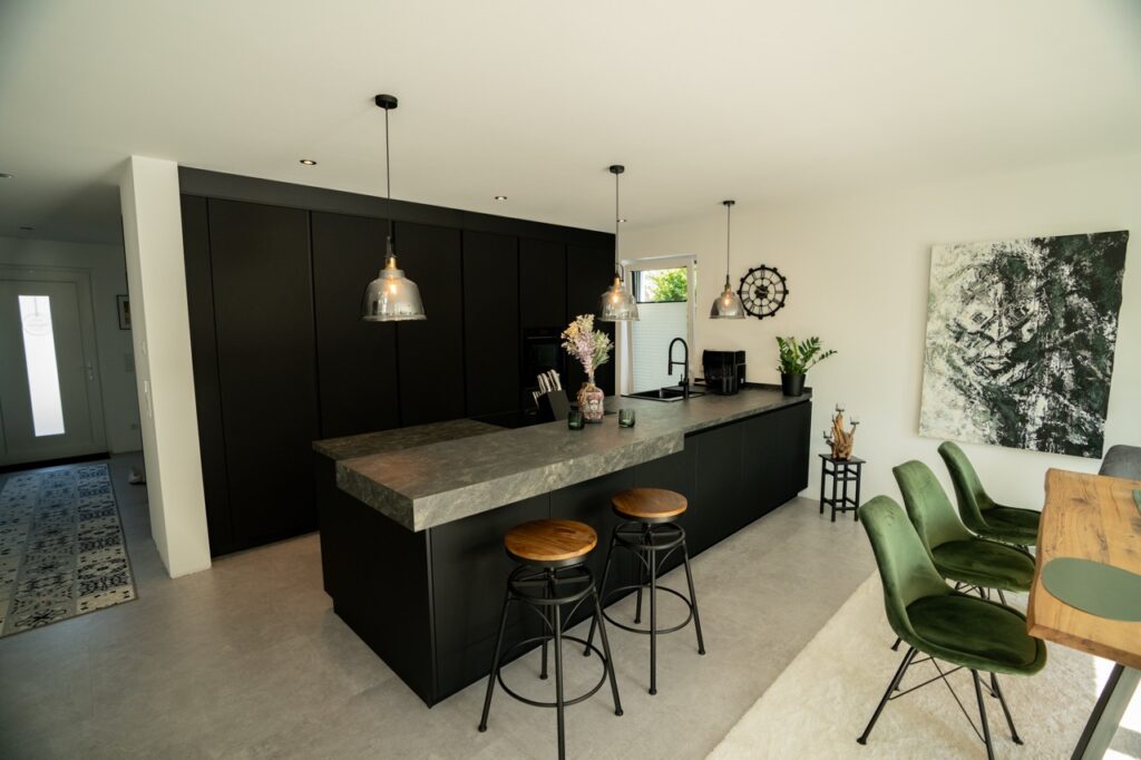 Moderne Küche mit grauer Insel, Hängelampen, Barhockern und Dekorationen in einem offenen Wohnraum.