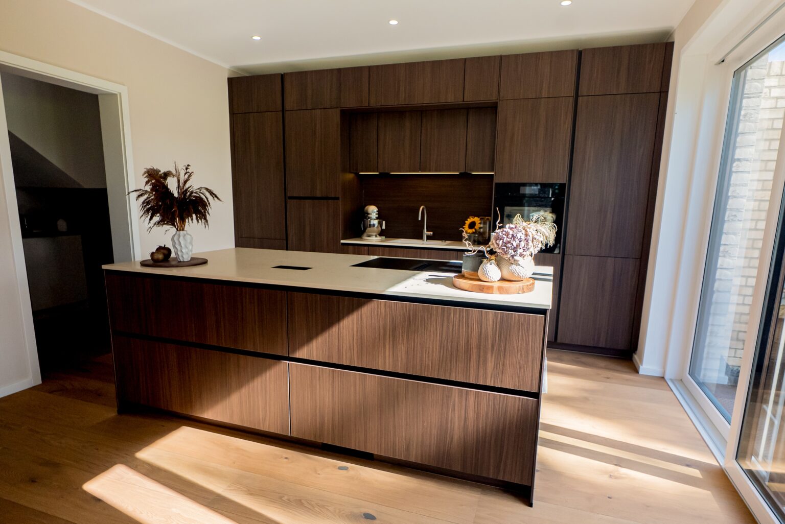 Moderne Küche mit dunklen Holzschränken, heller Arbeitsplatte und dekorativen Elementen.