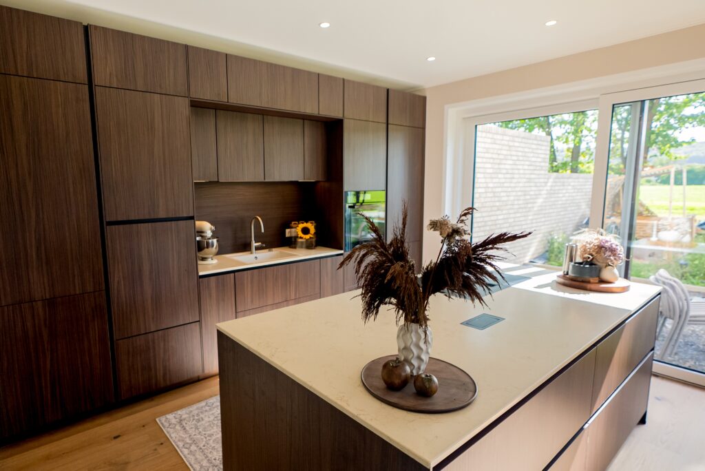 Moderne Küche mit dunklen Holzschränken, heller Arbeitsplatte und Vase mit getrockneten Pflanzen.