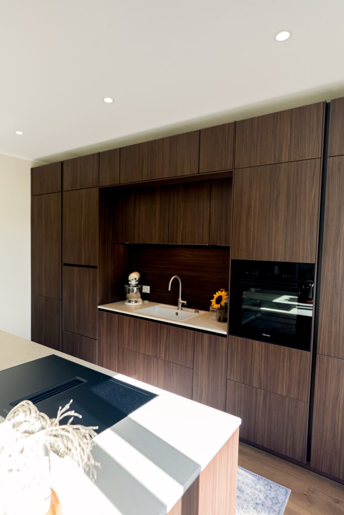 Moderne Küche mit dunklen Holzschränken, heller Arbeitsplatte und Sonnenblume als Farbakzent.