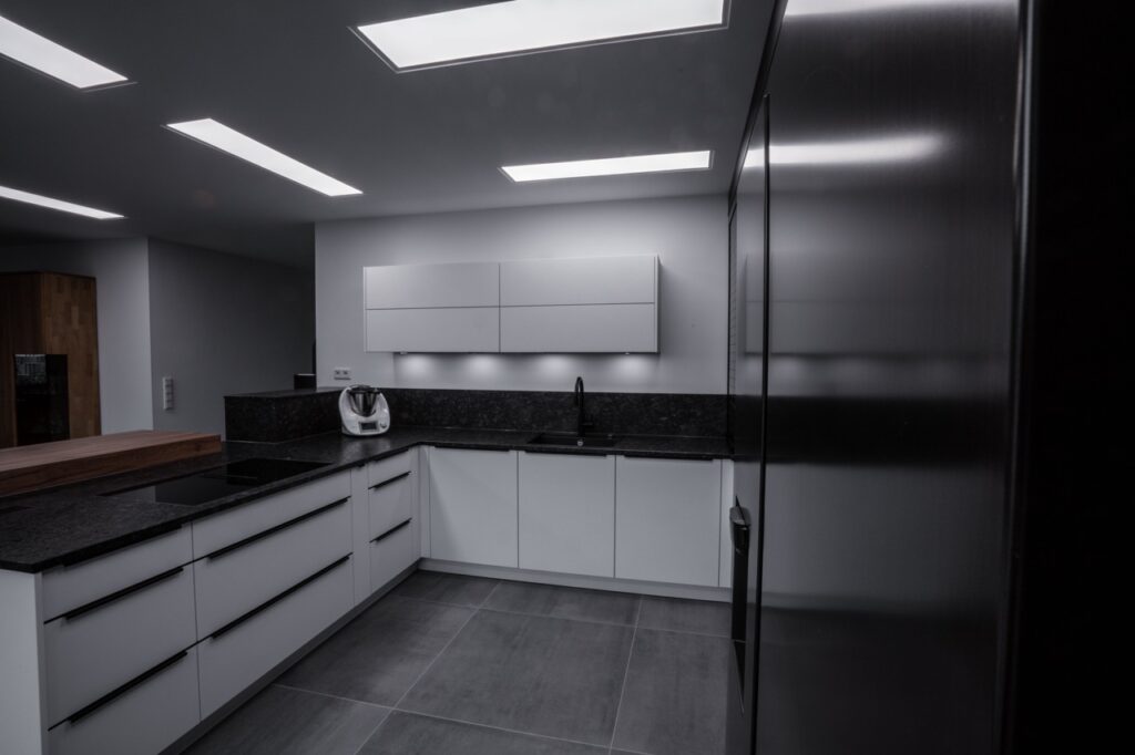 Moderne, minimalistische Küche mit weißen Schränken, dunkler Granitarbeitsplatte und schwarzen Akzenten.