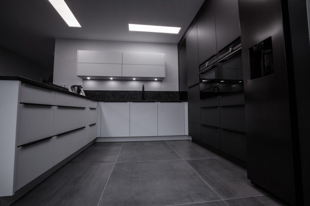 Moderne, minimalistische Küche in Schwarz-Weiß mit glatten Schränken und integrierten Geräten.