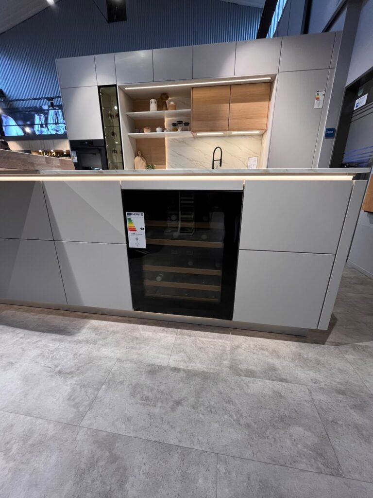 Moderne Küche mit grauen Schränken, marmorierter Arbeitsplatte und offenen Holzregalen.