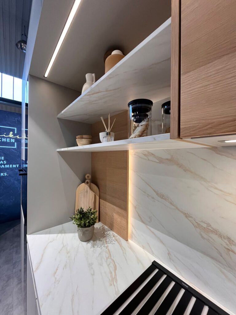 Moderne Küchenecke mit Holzregalen, Marmorelementen und Dekorationen in neutralen Tönen.