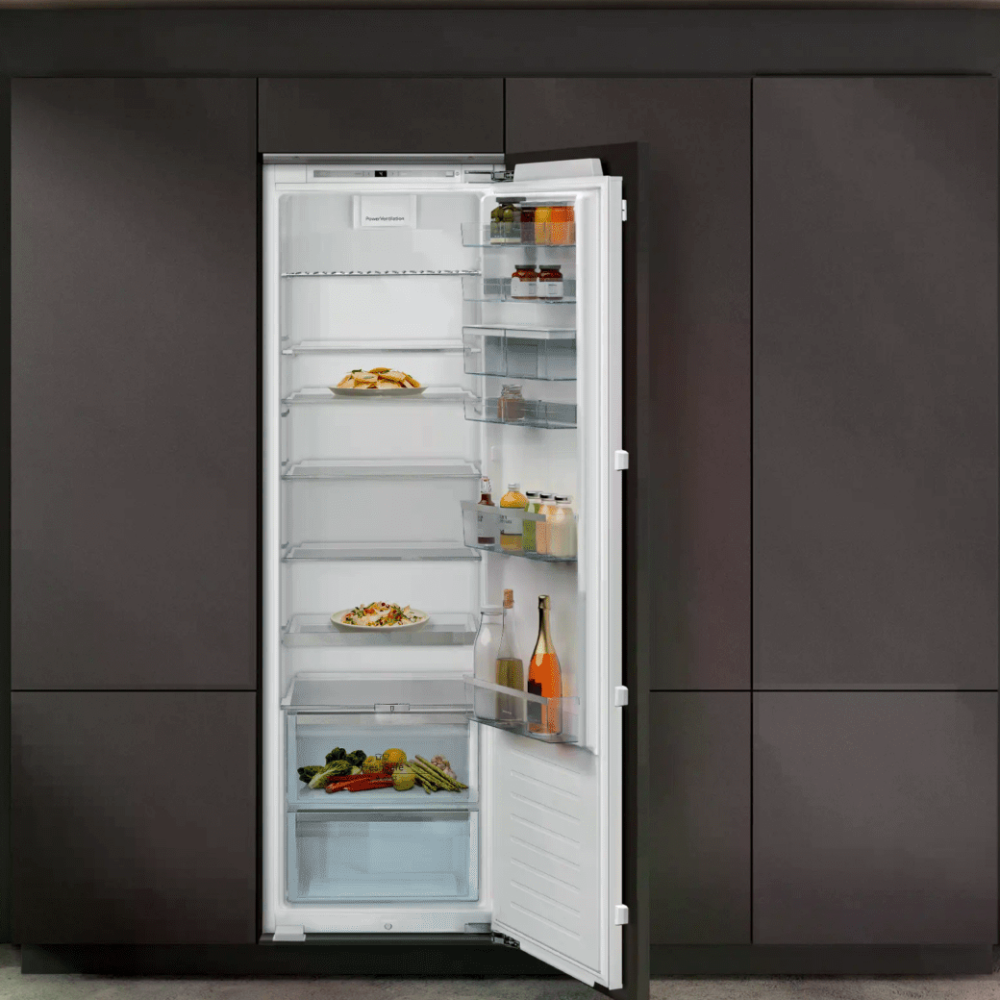 Moderne Küche mit offenem, gefülltem Kühlschrank, dunklen Schränken und großen Fenstern.