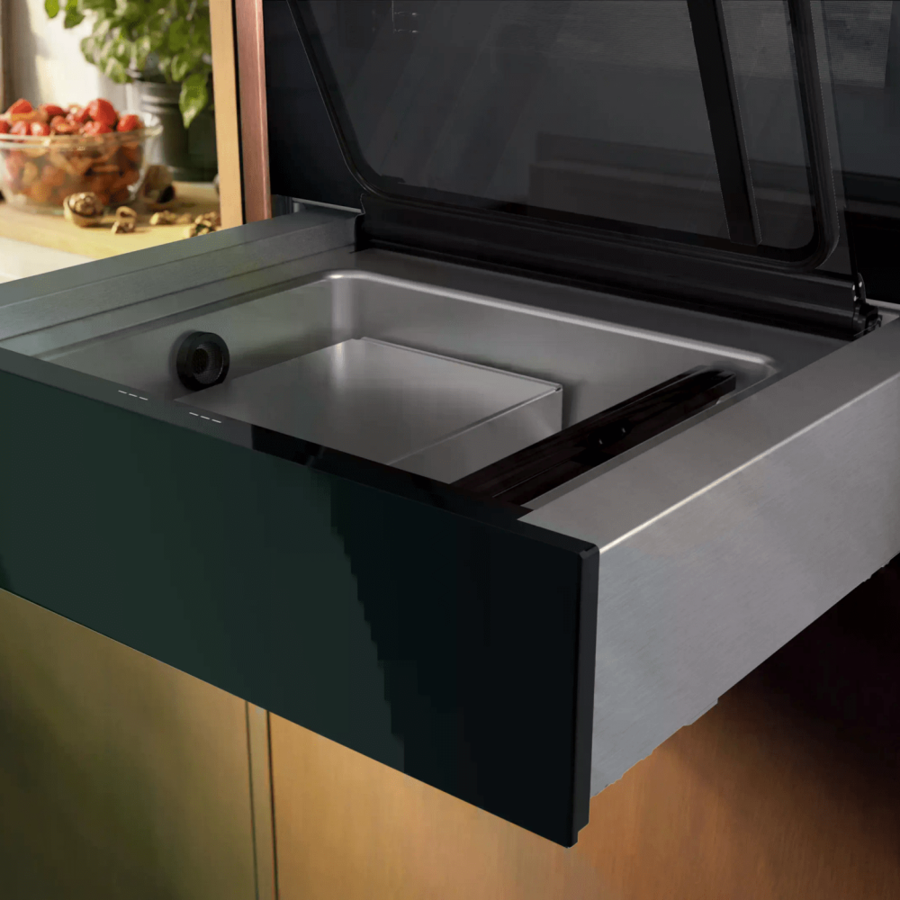 Moderne Küche mit offenem Vakuumiergerät, Erdbeeren und Ölflasche auf der Arbeitsplatte.