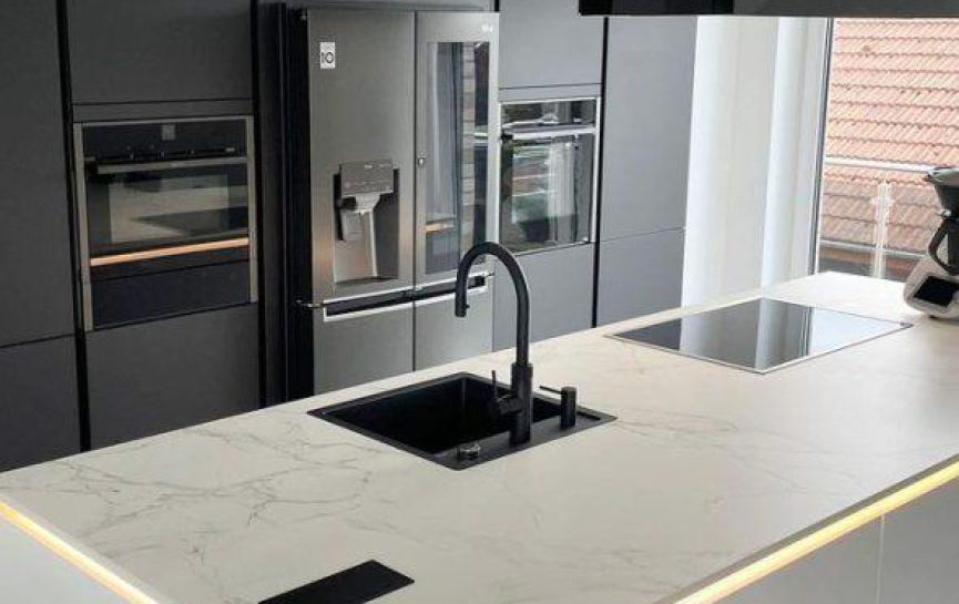 Moderne, minimalistische Küche mit marmorierter Insel, Edelstahlgeräten und monochromer Farbpalette.