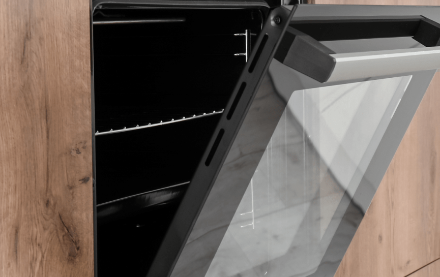 Moderner, eingebauter Backofen mit geöffneter Tür in einer hölzernen Kücheneinheit.