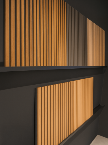 Moderne Wand mit vertikalen, hellen Holzpaneelen vor dunklem Hintergrund, elegant und minimalistisch.