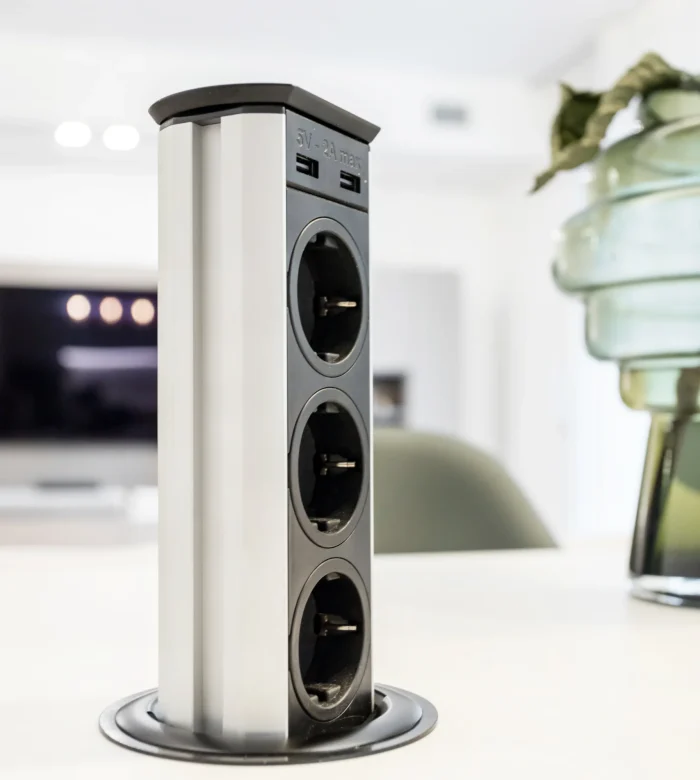 Versenkbare Steckdosenleiste mit USB-Anschlüssen, ausgefahren aus einer glatten, modernen Oberfläche.
