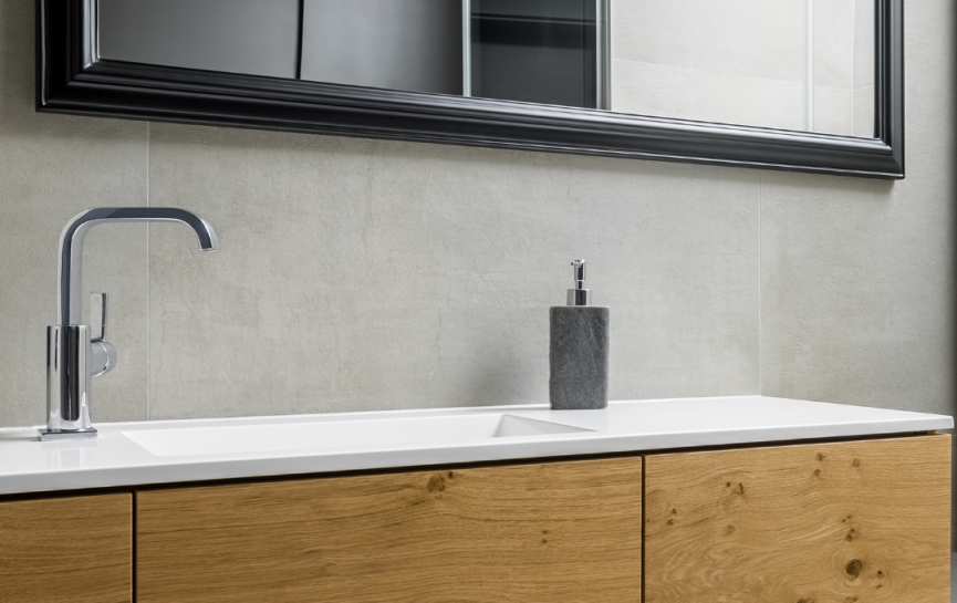 Modernes Badezimmer mit großem Spiegel, weißem Waschbecken, Holzunterschrank und grauem Seifenspender.