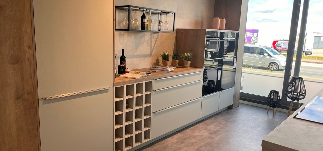 Moderne Küchenzeile in Beige mit Holzdetails, integriertem Weinregal und dekorativen Pflanzen.