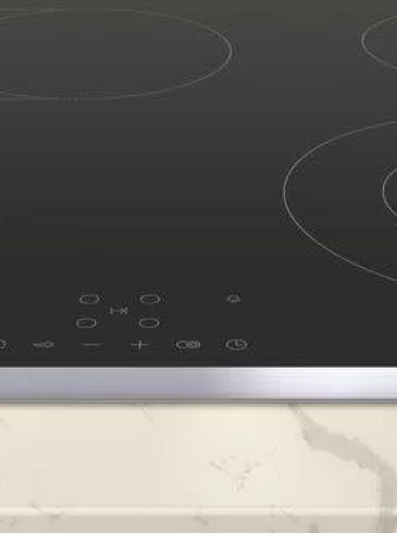 Moderne Induktionskochplatte mit schwarzer, glatter Oberfläche und silbernem Rand auf marmorierter Arbeitsplatte.
