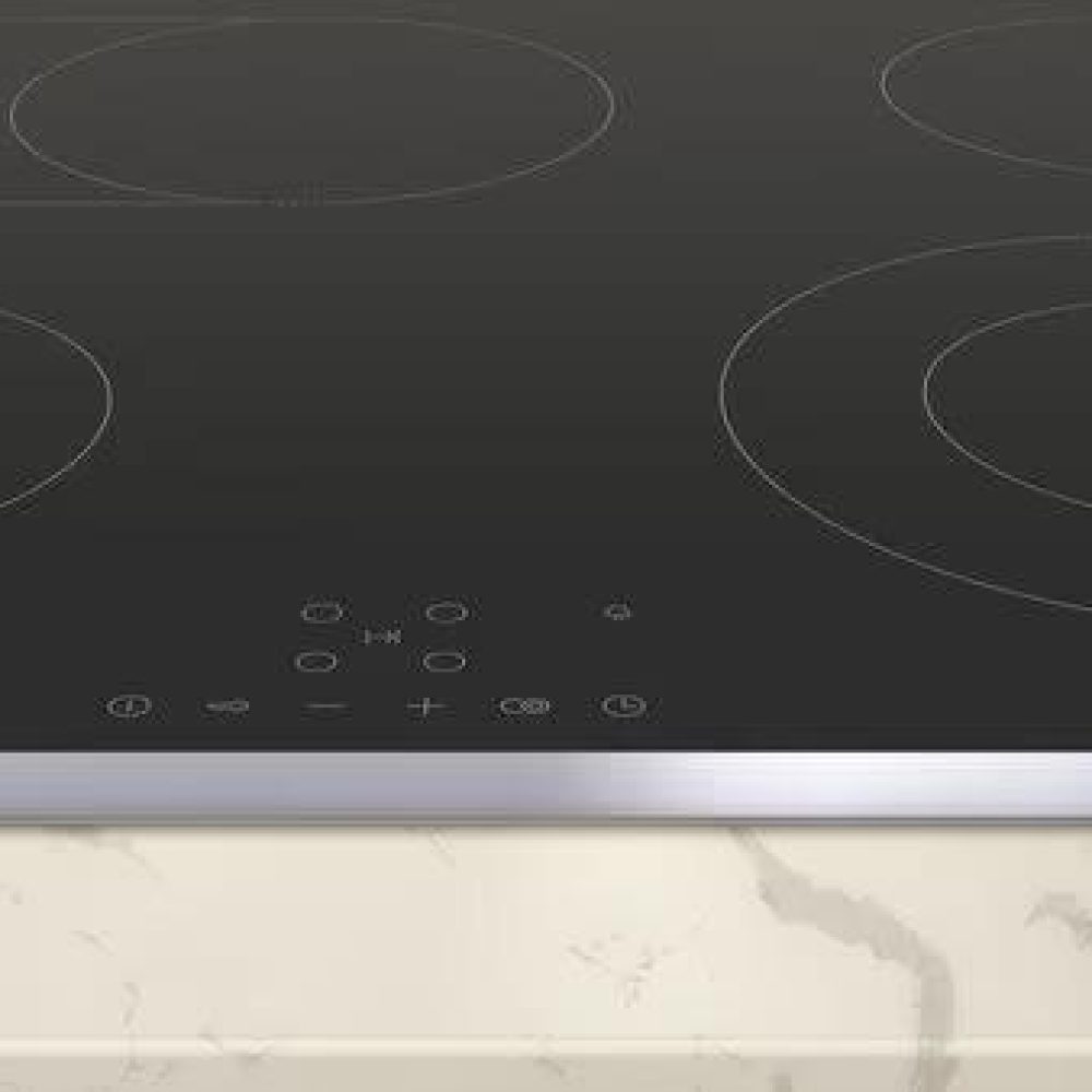 Moderne Induktionskochplatte mit schwarzer, glatter Oberfläche und silbernem Rand auf marmorierter Arbeitsplatte.