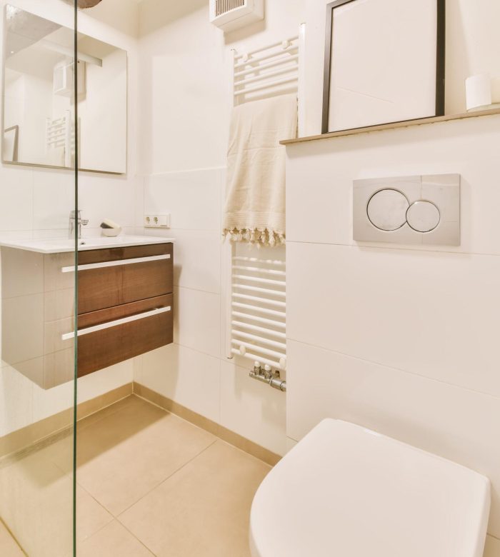 Modernes, minimalistisches Badezimmer mit weißem und beigem Design, Holzdetails und Glastrennwand.