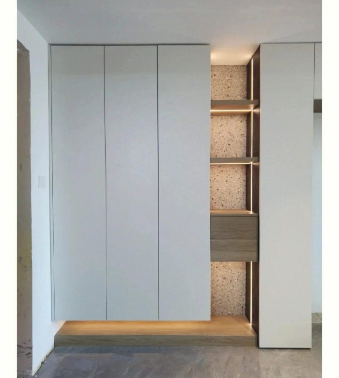 Moderner, minimalistischer Innenraum mit weißem Einbauschrank, offenen Regalen und grauem Steinboden.